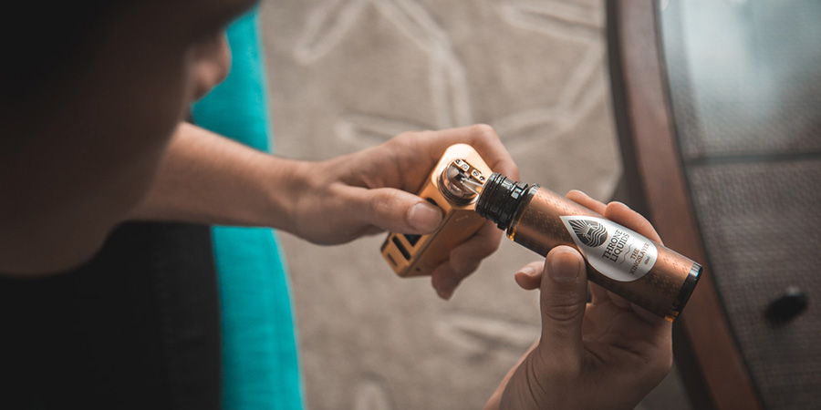 man holding a vape device and vape juice